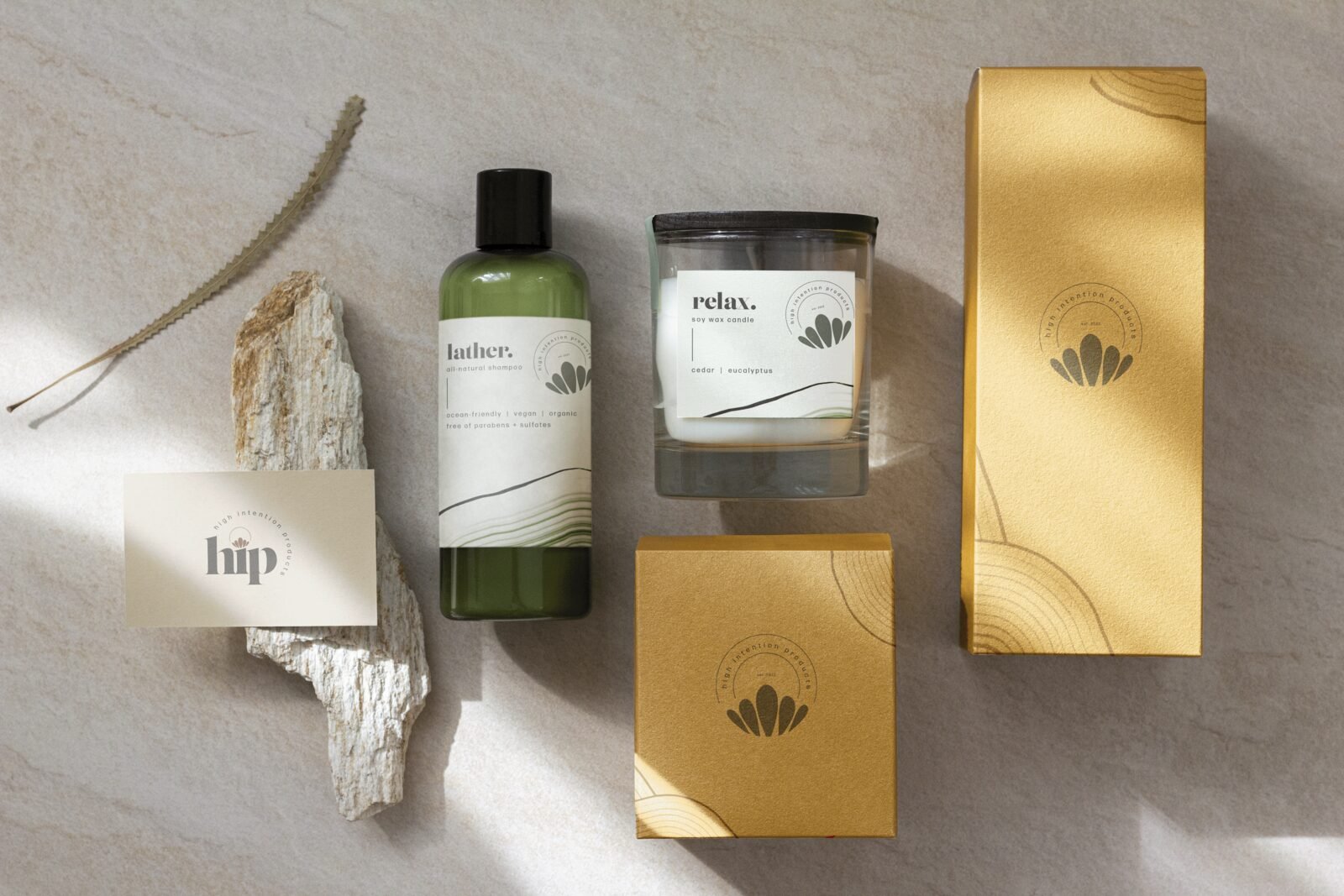 High Intention Products range: a wash bottle, a candle and gold packaging arranged on stone